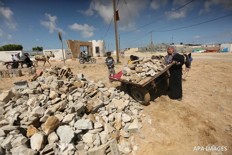 Palestinian woman Jihan Abu Muhsen collects bricks for sale with her son Mohammad from the ruins of a house destroyed during the 2014 war in Khan Younis in the southern Gaza Strip March 17, 2016. Abu Muhsen gathers brick...