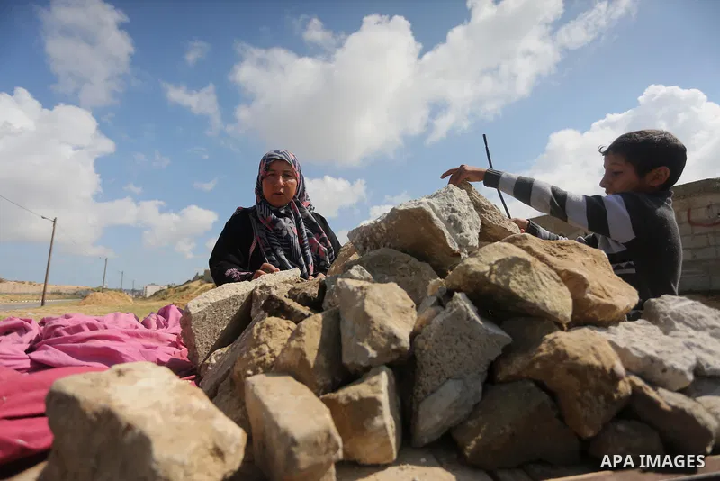 Palestinian woman Jihan Abu Muhsen collects bricks for sale with her son Mohammad from the ruins of a house destroyed during the 2014 war in Khan Younis in the southern Gaza Strip March 17, 2016. Abu Muhsen gathers brick...