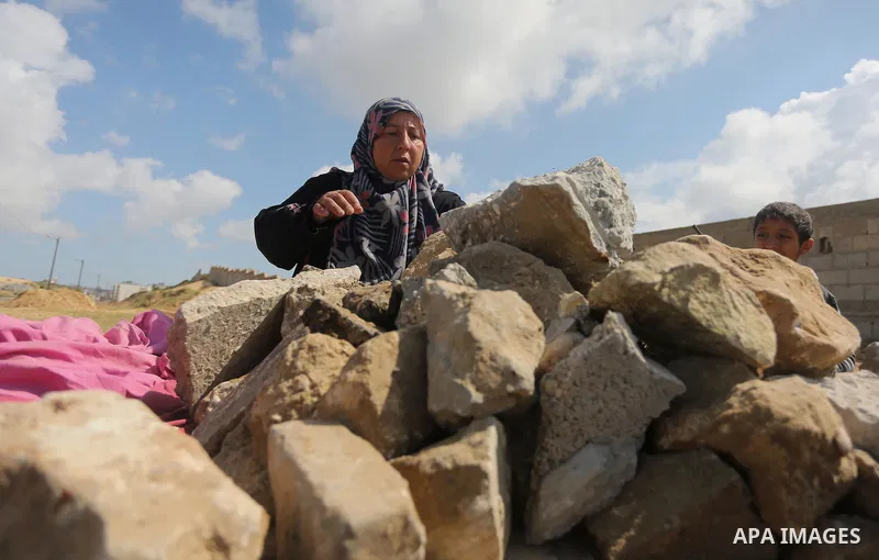 Palestinian woman Jihan Abu Muhsen collects bricks for sale with her son Mohammad from the ruins of a house destroyed during the 2014 war in Khan Younis in the southern Gaza Strip March 17, 2016. Abu Muhsen gathers brick...