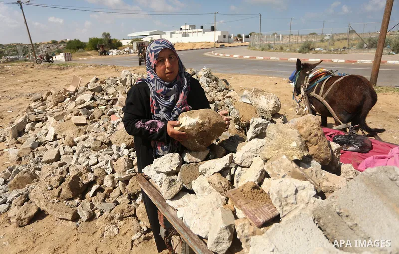 Palestinian woman Jihan Abu Muhsen collects bricks for sale with her son Mohammad from the ruins of a house destroyed during the 2014 war in Khan Younis in the southern Gaza Strip March 17, 2016. Abu Muhsen gathers brick...