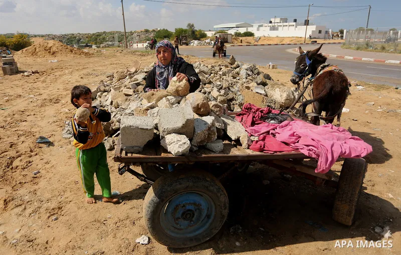 Palestinian woman Jihan Abu Muhsen collects bricks for sale with her son Mohammad from the ruins of a house destroyed during the 2014 war in Khan Younis in the southern Gaza Strip March 17, 2016. Abu Muhsen gathers brick...