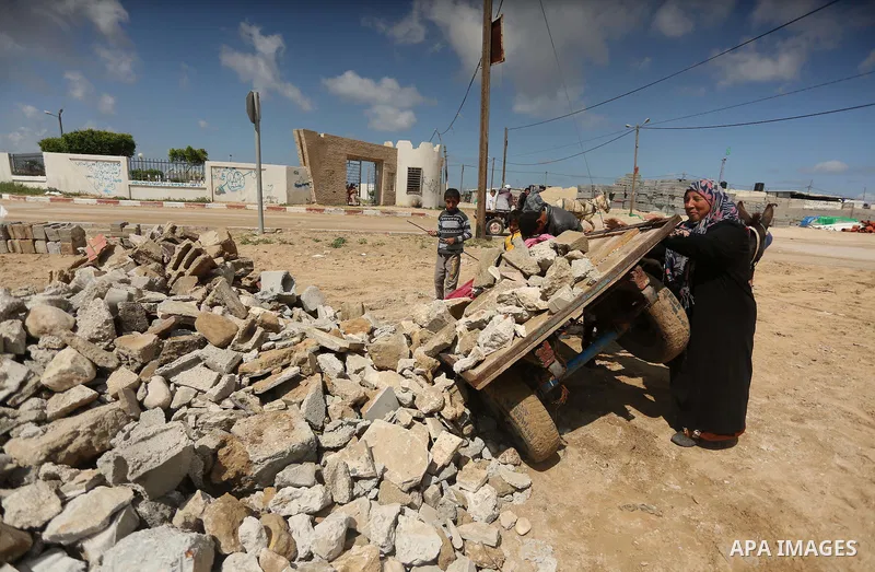 Palestinian woman Jihan Abu Muhsen collects bricks for sale with her son Mohammad from the ruins of a house destroyed during the 2014 war in Khan Younis in the southern Gaza Strip March 17, 2016. Abu Muhsen gathers brick...