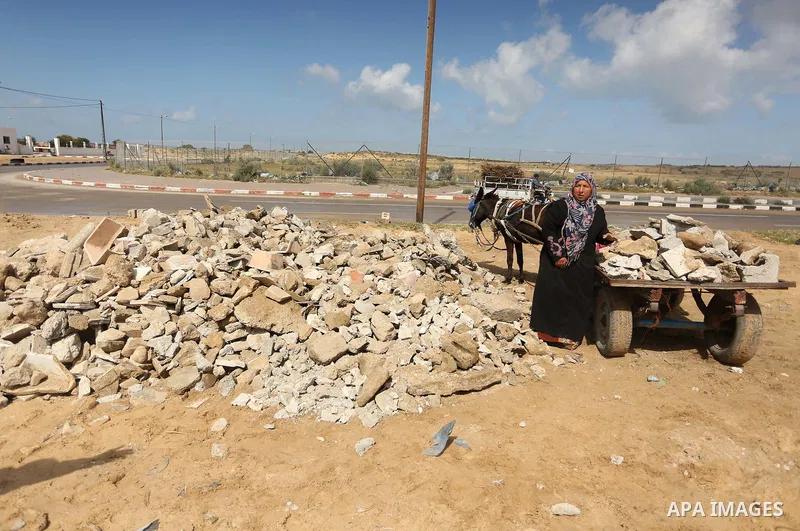 Palestinian woman Jihan Abu Muhsen collects bricks for sale with her son Mohammad from the ruins of a house destroyed during the 2014 war in Khan Younis in the southern Gaza Strip March 17, 2016. Abu Muhsen gathers brick...
