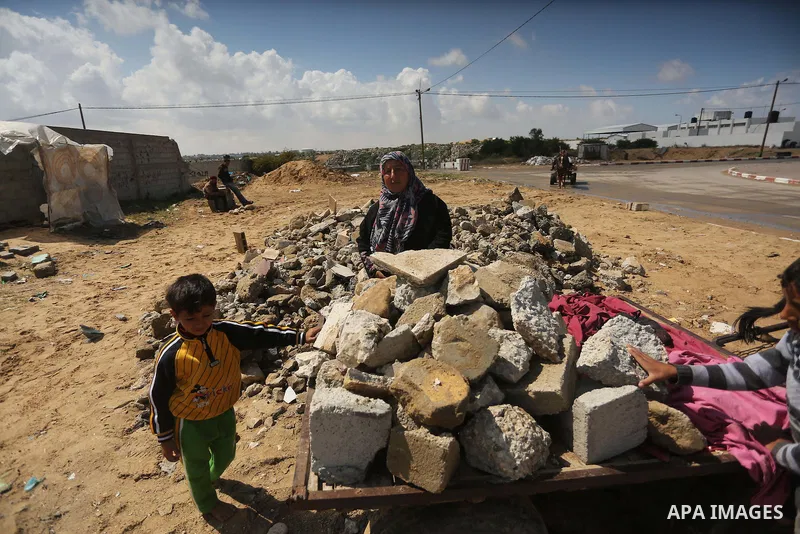 Palestinian woman Jihan Abu Muhsen collects bricks for sale with her son Mohammad from the ruins of a house destroyed during the 2014 war in Khan Younis in the southern Gaza Strip March 17, 2016. Abu Muhsen gathers brick...