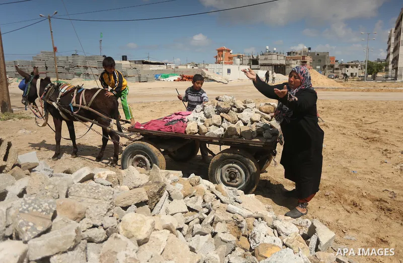 Palestinian woman Jihan Abu Muhsen collects bricks for sale with her son Mohammad from the ruins of a house destroyed during the 2014 war in Khan Younis in the southern Gaza Strip March 17, 2016. Abu Muhsen gathers brick...