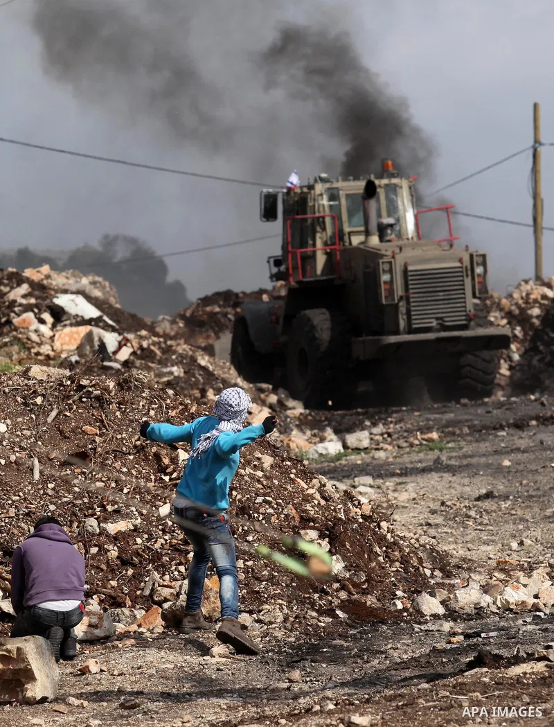 Palestinian protesters hurl stones at an Israeli military bulldozer during clashes following a demonstration against the expropriation of Palestinian land by Israel in the village of Kfar Qaddum, near Nablus, in the occu...