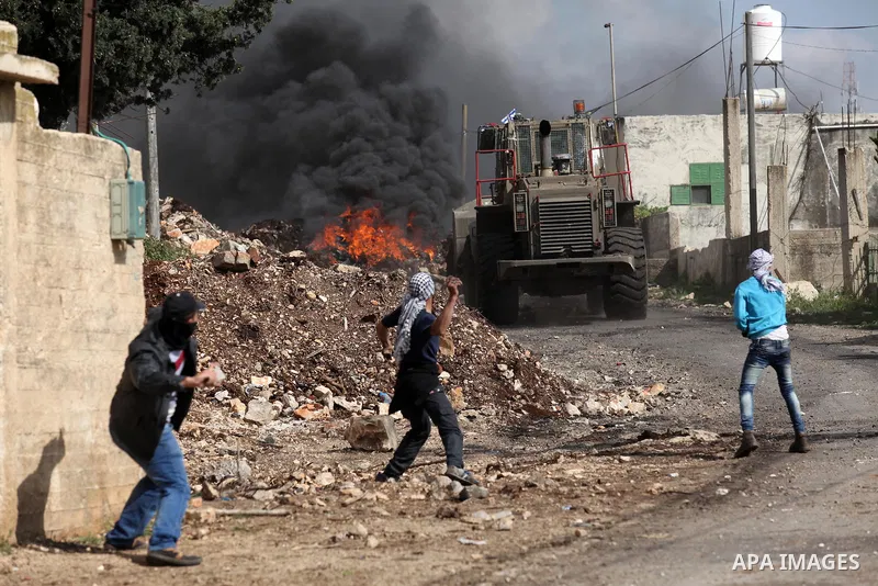 Palestinian protesters hurl stones at an Israeli military bulldozer during clashes following a demonstration against the expropriation of Palestinian land by Israel in the village of Kfar Qaddum, near Nablus, in the occu...