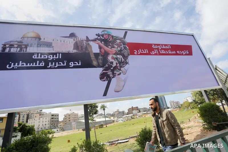 Palestinians walk past a placard depicting a member of the Ezzedine al-Qassam Brigades, the armed wing of the Hamas movement in Gaza city on March 20, 2016. Photo by Mohammed Asad