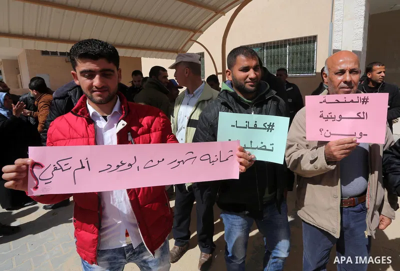 Palestinians who beneficiaries from Kuwaiti grant hold placards during a protest demanding to reconstruction of their homes which destroyed during 2014 war in Gaza city on March 20, 2016. Photo by Mohammed Asad
