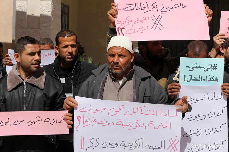 Palestinians who beneficiaries from Kuwaiti grant hold placards during a protest demanding to reconstruction of their homes which destroyed during 2014 war in Gaza city on March 20, 2016. Photo by Mohammed Asad