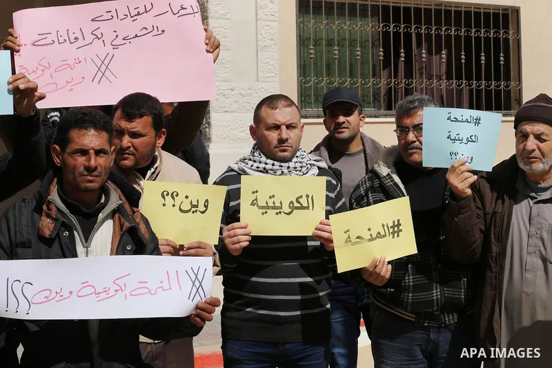 Palestinians who beneficiaries from Kuwaiti grant hold placards during a protest demanding to reconstruction of their homes which destroyed during 2014 war in Gaza city on March 20, 2016. Photo by Mohammed Asad
