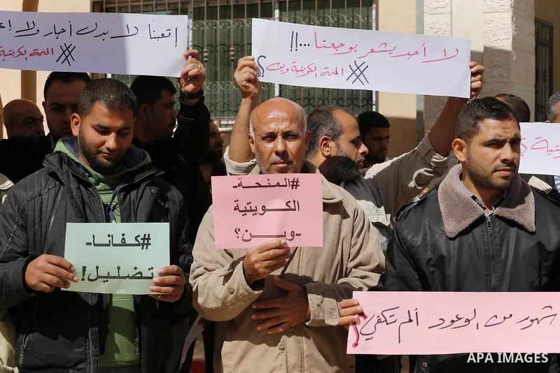Palestinians who beneficiaries from Kuwaiti grant hold placards during a protest demanding to reconstruction of their homes which destroyed during 2014 war in Gaza city on March 20, 2016. Photo by Mohammed Asad