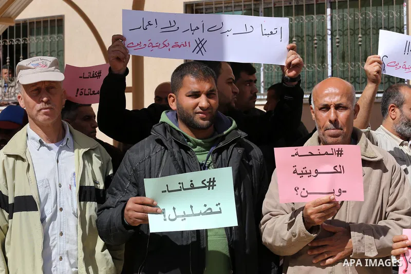 Palestinians who beneficiaries from Kuwaiti grant hold placards during a protest demanding to reconstruction of their homes which destroyed during 2014 war in Gaza city on March 20, 2016. Photo by Mohammed Asad