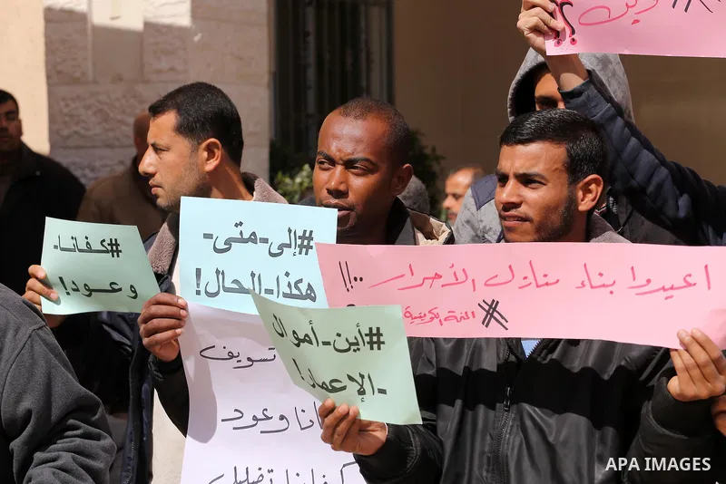 Palestinians who beneficiaries from Kuwaiti grant hold placards during a protest demanding to reconstruction of their homes which destroyed during 2014 war in Gaza city on March 20, 2016. Photo by Mohammed Asad