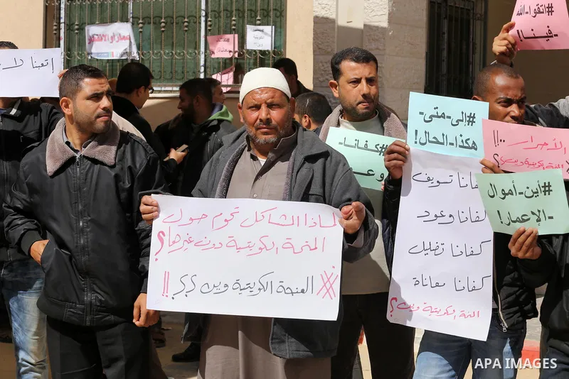 Palestinians who beneficiaries from Kuwaiti grant hold placards during a protest demanding to reconstruction of their homes which destroyed during 2014 war in Gaza city on March 20, 2016. Photo by Mohammed Asad