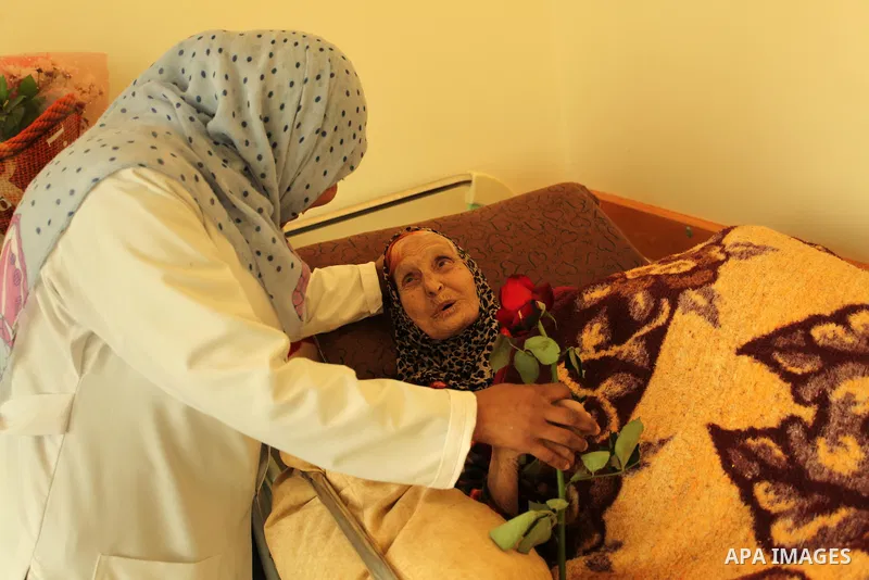 A Palestinian nurse distributes flowers at the elderly woman to mark the anniversary of Mother's Day, at Al-Wafa association for the elderly in Gaza city on March 21, 2016. Photo by Ashraf Amra