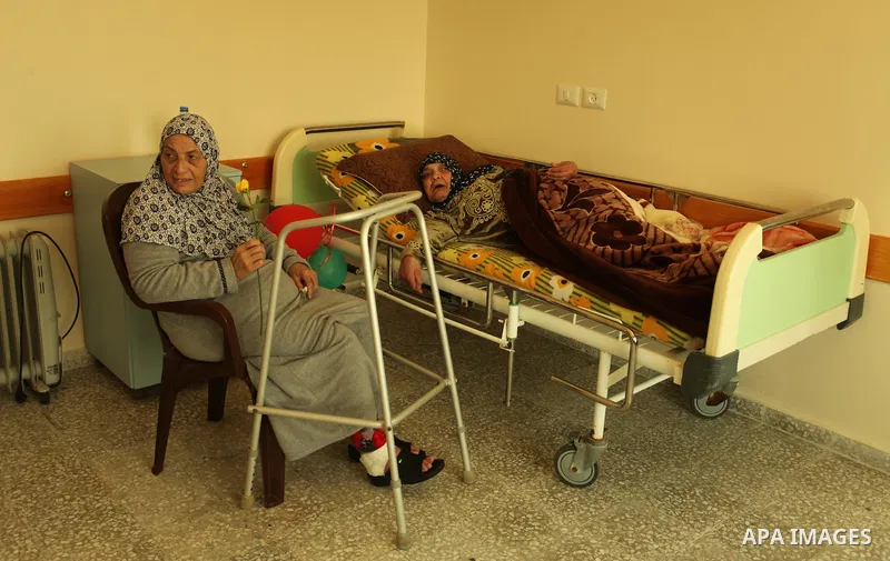 A Palestinian elderly woman holds flowers to mark the anniversary of Mother's Day, at Al-Wafa association for the elderly in Gaza city on March 21, 2016. Photo by Ashraf Amra