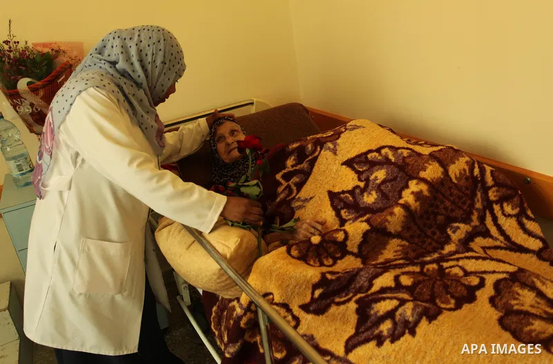 A Palestinian nurse distributes flowers at the elderly woman to mark the anniversary of Mother's Day, at Al-Wafa association for the elderly in Gaza city on March 21, 2016. Photo by Ashraf Amra