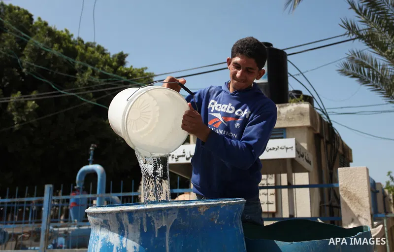 Palestinian children fill plastic bottles and jerry cans with drinking water from a public tap marking the Water World Day in Beit Lahia in the northern Gaza Strip, on March 22, 2016. Photo by Ashraf Amra