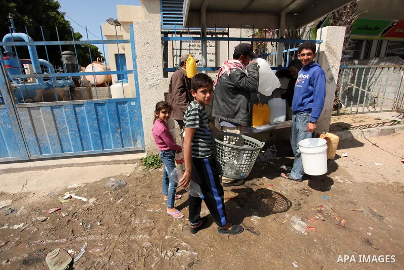 Palestinian children fill plastic bottles and jerry cans with drinking water from a public tap marking the Water World Day in Beit Lahia in the northern Gaza Strip, on March 22, 2016. Photo by Ashraf Amra