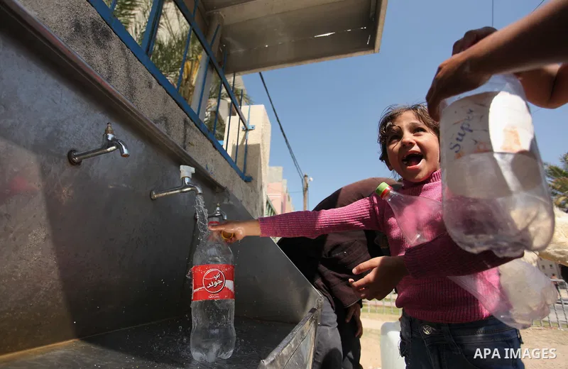 Palestinian children fill plastic bottles and jerry cans with drinking water from a public tap marking the Water World Day in Beit Lahia in the northern Gaza Strip, on March 22, 2016. Photo by Ashraf Amra