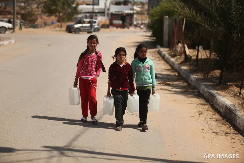 Palestinian children fill plastic bottles and jerry cans with drinking water from a public tap marking the Water World Day in Beit Lahia in the northern Gaza Strip, on March 22, 2016. Photo by Ashraf Amra