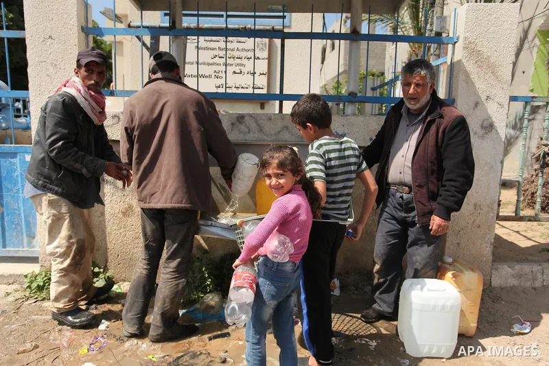 Palestinian children fill plastic bottles and jerry cans with drinking water from a public tap marking the Water World Day in Beit Lahia in the northern Gaza Strip, on March 22, 2016. Photo by Ashraf Amra