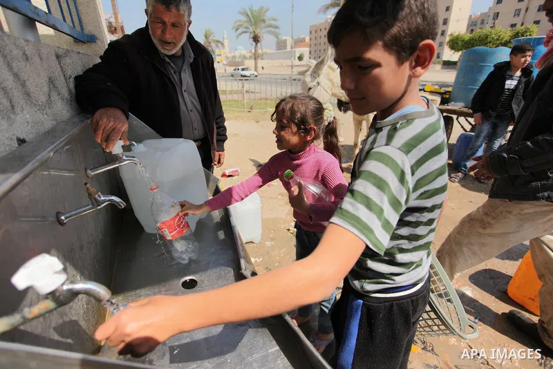 Palestinian children fill plastic bottles and jerry cans with drinking water from a public tap marking the Water World Day in Beit Lahia in the northern Gaza Strip, on March 22, 2016. Photo by Ashraf Amra