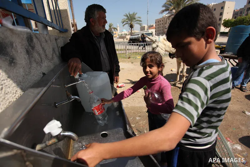 Palestinian children fill plastic bottles and jerry cans with drinking water from a public tap marking the Water World Day in Beit Lahia in the northern Gaza Strip, on March 22, 2016. Photo by Ashraf Amra