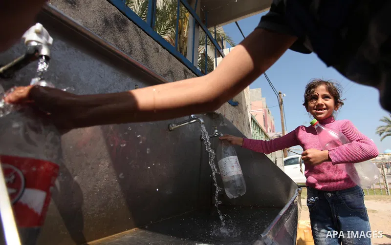 Palestinian children fill plastic bottles and jerry cans with drinking water from a public tap marking the Water World Day in Beit Lahia in the northern Gaza Strip, on March 22, 2016. Photo by Ashraf Amra