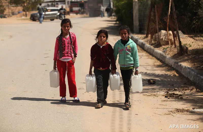 Palestinian children fill plastic bottles and jerry cans with drinking water from a public tap marking the Water World Day in Beit Lahia in the northern Gaza Strip, on March 22, 2016. Photo by Ashraf Amra