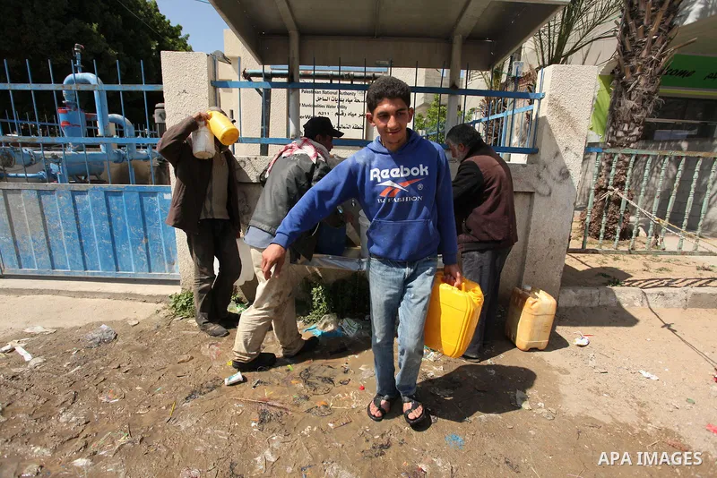 Palestinian children fill plastic bottles and jerry cans with drinking water from a public tap marking the Water World Day in Beit Lahia in the northern Gaza Strip, on March 22, 2016. Photo by Ashraf Amra