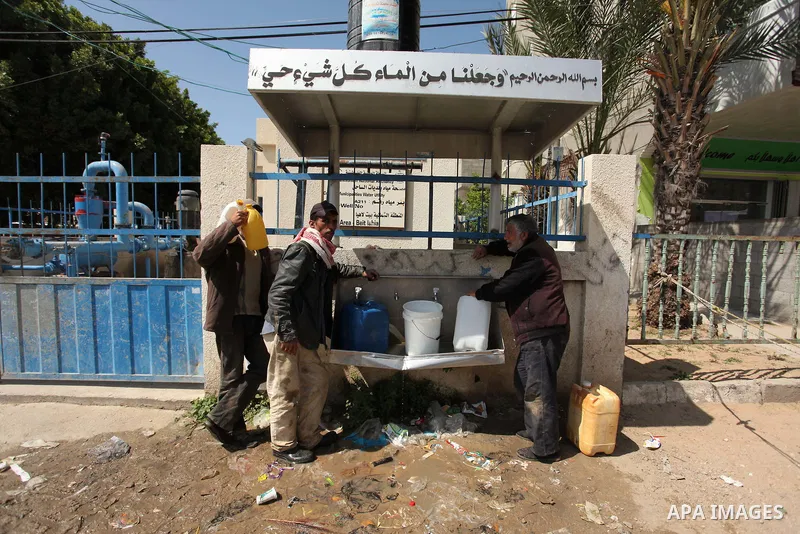 Palestinian children fill plastic bottles and jerry cans with drinking water from a public tap marking the Water World Day in Beit Lahia in the northern Gaza Strip, on March 22, 2016. Photo by Ashraf Amra