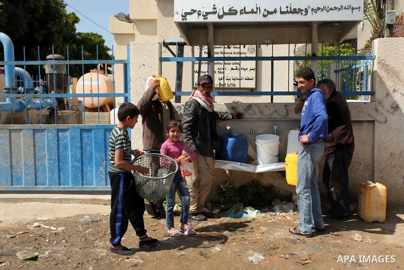 Palestinian children fill plastic bottles and jerry cans with drinking water from a public tap marking the Water World Day in Beit Lahia in the northern Gaza Strip, on March 22, 2016. Photo by Ashraf Amra