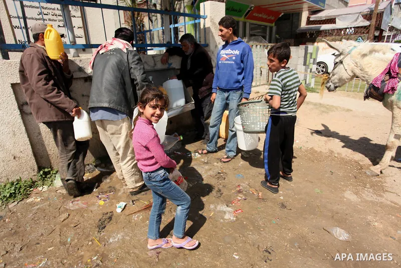 Palestinian children fill plastic bottles and jerry cans with drinking water from a public tap marking the Water World Day in Beit Lahia in the northern Gaza Strip, on March 22, 2016. Photo by Ashraf Amra
