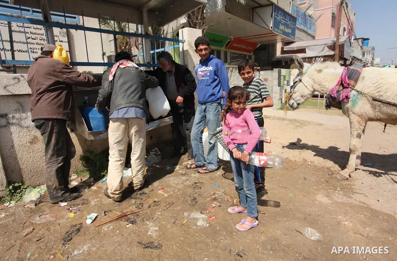 Palestinian children fill plastic bottles and jerry cans with drinking water from a public tap marking the Water World Day in Beit Lahia in the northern Gaza Strip, on March 22, 2016. Photo by Ashraf Amra