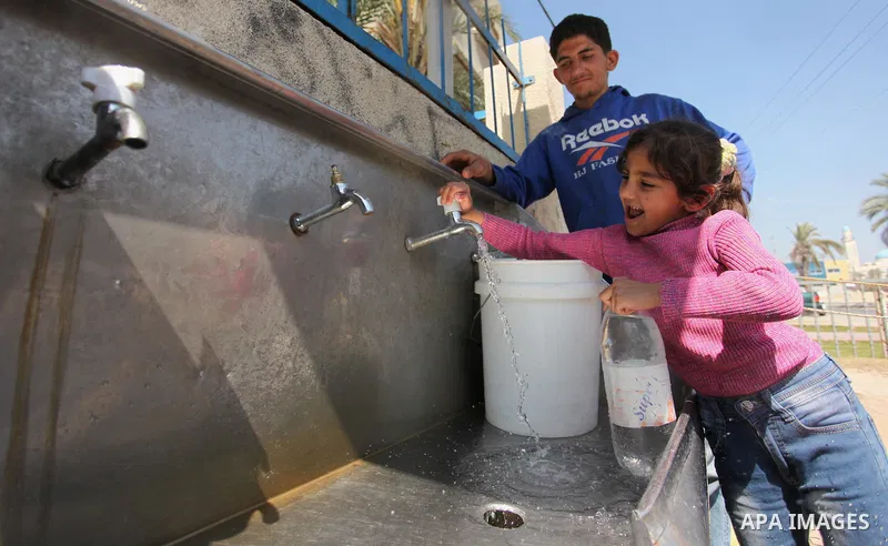 Palestinian children fill plastic bottles and jerry cans with drinking water from a public tap marking the Water World Day in Beit Lahia in the northern Gaza Strip, on March 22, 2016. Photo by Ashraf Amra