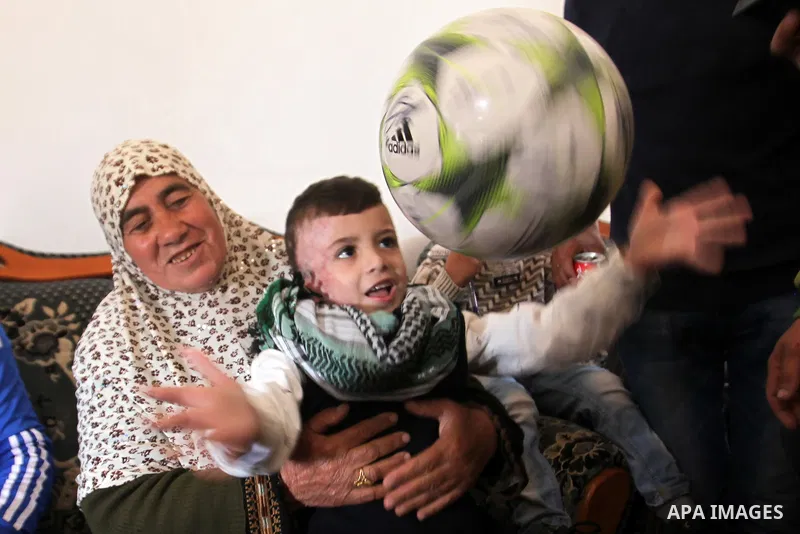 Palestinian boy Ahmed Dawabsha, 5, who suffered severe burns in an arson attack by suspected Jewish attackers on his family home last July and in which his younger brother, Ali, and his parents both died, is welcomed by...