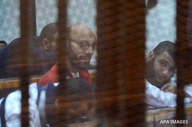 Defendants of Egyptian Muslim Brotherhood sit behind bars during the 'Qatar espionage' case, along with ousted Islamist president Mohamed Morsi (unseen) in a court in Cairo on March 23, 2016. The defendants are accused o...