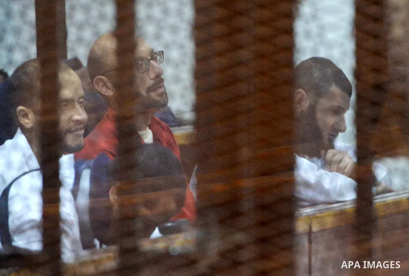 Defendants of Egyptian Muslim Brotherhood sit behind bars during the 'Qatar espionage' case, along with ousted Islamist president Mohamed Morsi (unseen) in a court in Cairo on March 23, 2016. The defendants are accused o...