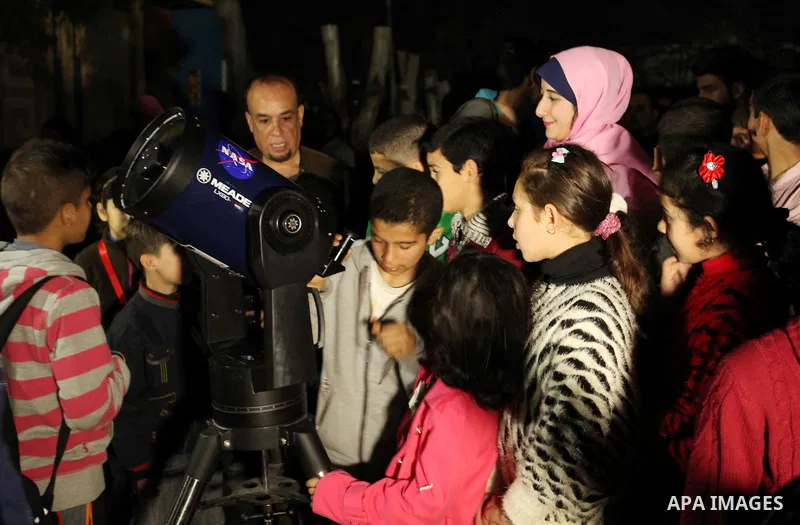 Palestinian children look through a telescope to watch the moon and stars at Al-qattan center in Gaza city on March 23, 2016. Photo by Ashraf Amra