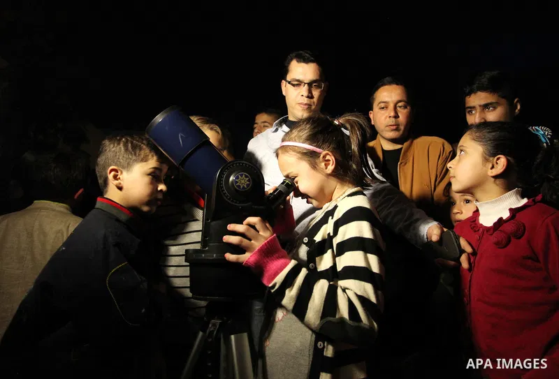 Palestinian children look through a telescope to watch the moon and stars at Al-qattan center in Gaza city on March 23, 2016. Photo by Ashraf Amra