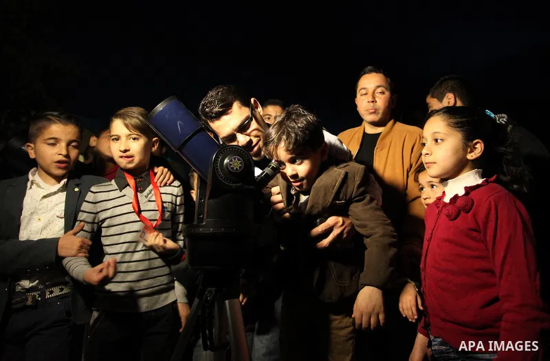 Palestinian children look through a telescope to watch the moon and stars at Al-qattan center in Gaza city on March 23, 2016. Photo by Ashraf Amra