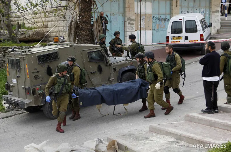 Israeli security forces carry the body of a Palestinian man tried to stab an Israeli soldier before being shot dead, in the Israeli occupied West Bank city of Hebron, on March 24, 2016. Two Palestinians were killed by Is...