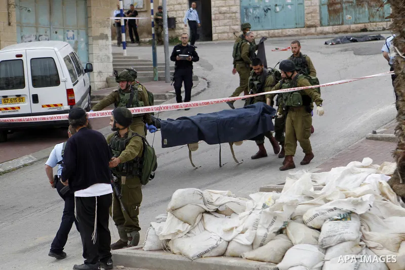 Israeli security forces carry the body of a Palestinian man tried to stab an Israeli soldier before being shot dead, in the Israeli occupied West Bank city of Hebron, on March 24, 2016. Two Palestinians were killed by Is...