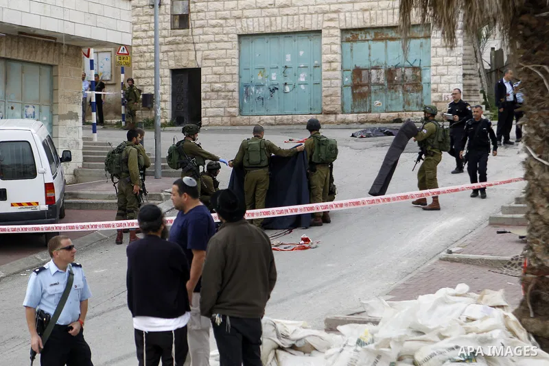 Israeli security forces carry the body of a Palestinian man tried to stab an Israeli soldier before being shot dead, in the Israeli occupied West Bank city of Hebron, on March 24, 2016. Two Palestinians were killed by Is...