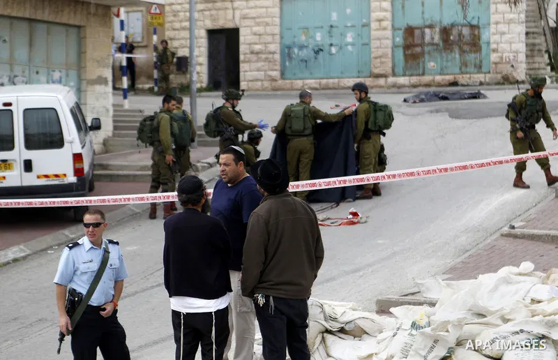 Israeli security forces carry the body of a Palestinian man tried to stab an Israeli soldier before being shot dead, in the Israeli occupied West Bank city of Hebron, on March 24, 2016. Two Palestinians were killed by Is...