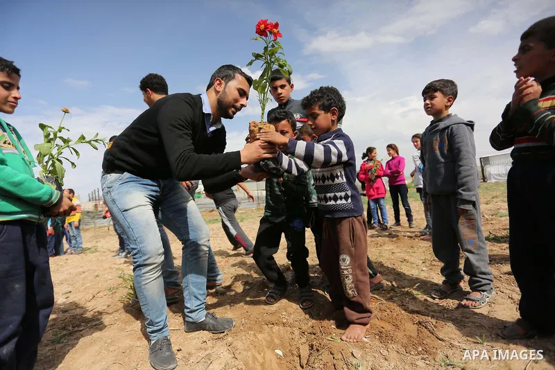 Palestinian children are grown roses during a rally demanding to reconstruction of their homes which destroyed during 2014 war in Shejaiya neighborhood in Gaza city, on March 24, 2016. Photo by Ashraf Amra
