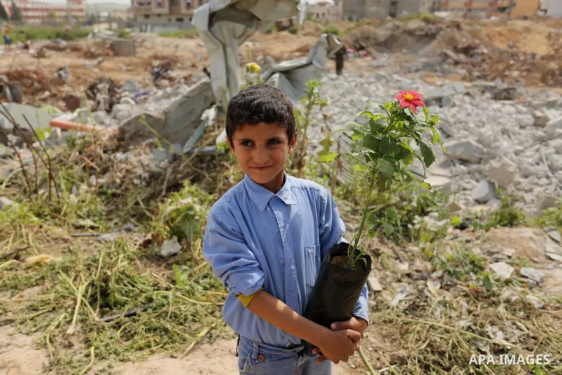 Palestinian children are grown roses during a rally demanding to reconstruction of their homes which destroyed during 2014 war in Shejaiya neighborhood in Gaza city, on March 24, 2016. Photo by Ashraf Amra