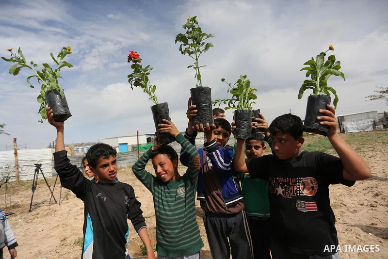 Palestinian children are grown roses during a rally demanding to reconstruction of their homes which destroyed during 2014 war in Shejaiya neighborhood in Gaza city, on March 24, 2016. Photo by Ashraf Amra